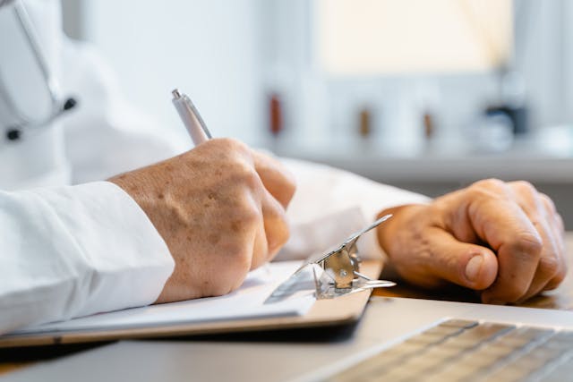 a doctor's hand writing a medical record with a pen